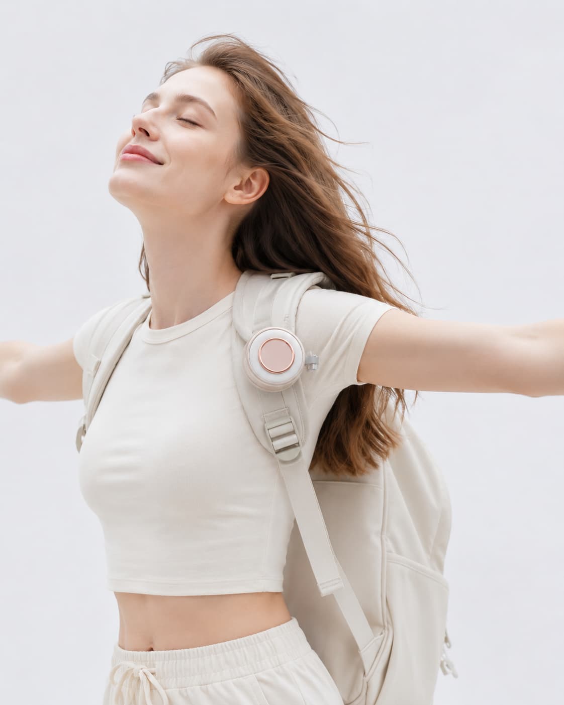 A lifestyle showcase of the pink BreezeClip portable fan magnetically attached to a backpack shoulder strap for hands-free outdoor cooling while hiking.